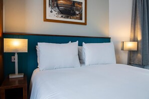 A neatly made bed with white linens, two bedside lamps, and a framed picture on the wall. - Best Western Middlesbrough (Middlesbrough)