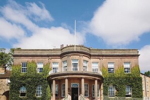 A historic building with a central circular balcony, multiple windows, and a flagpole. - Wood Hall Hotel & Spa (Wetherby)