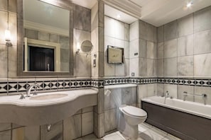 A bathroom with a large mirror, a sink, a toilet, and a bathtub. - Wood Hall Hotel & Spa (Wetherby)
