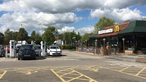 Un estacionamiento con estaciones de carga para vehículos eléctricos, un restaurante McDonald's y un camino de ladrillo.