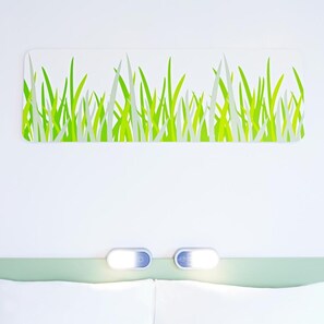 Una cama con cabecera verde y una lámpara de pared.