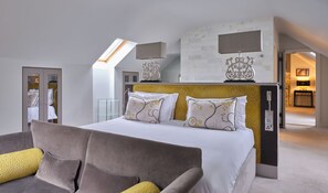 A modern bedroom with a large bed, a sofa, a glass shelving unit, and a view of a bathroom. - The Mole Resort (Umberleigh)