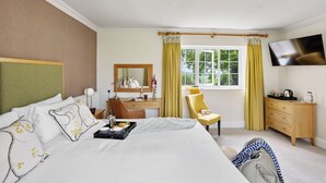 A hotel room with a bed, a desk, a chair, a dresser, a TV, and a window with curtains. - The Mole Resort (Umberleigh)