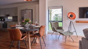A modern kitchen with a dining area, a large window, and a floor lamp. - The Mole Resort (Umberleigh)