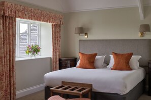 A bedroom with a large bed, two bedside lamps, a nightstand, a wooden bench, and a window with curtains. - The Mole Resort (Umberleigh)