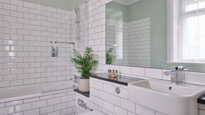 A modern bathroom with white subway tiles, a bathtub, a sink, and a toilet. - The Mole Resort (Umberleigh)