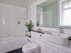 A modern bathroom with white subway tiles, a bathtub, a sink, and a toilet. - The Mole Resort (Umberleigh)