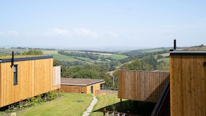 A modern wooden building with a view of rolling hills. - The Mole Resort (Umberleigh)