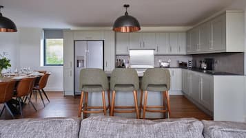 A modern kitchen with grey cabinets, a central island with stools, and a dining area with a table set for four.