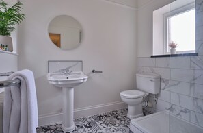 A bathroom with a pedestal sink, toilet, and bathtub. - The Mole Resort (Umberleigh)