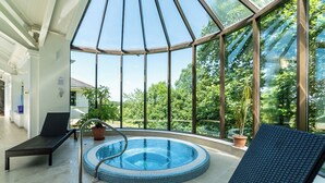 A glass-enclosed indoor pool area with lounge chairs, a hot tub, and potted plants. - The Mole Resort (Umberleigh)
