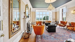 A spacious room with a large mirror, a chandelier, and a view of the outdoors. - The Mole Resort (Umberleigh)
