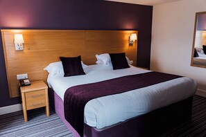 A hotel room with a bed, bedside table, lamp, and a mirror on the wall. - Ayre Hotel (Kirkwall)