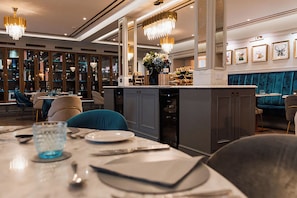 A restaurant interior with a bar area, seating, and a decorative chandelier. - Ayre Hotel (Kirkwall)