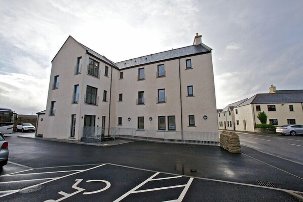 A multi-story building with a parking lot in front. - Ayre Hotel (Kirkwall)