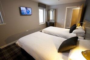 Ein Hotelzimmer mit zwei Betten, einem Fernseher, einem Spiegel und einer Tür.