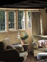 A cozy room with a large window, a small table with a vase of flowers, and two armchairs.