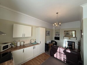 A compact kitchen with white cabinetry, a microwave, and a sink. - Spring Garden Guest House (Gosport)