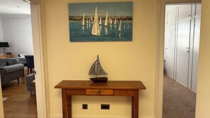 A living room with a wooden table, a sailboat model, and a painting of sailboats on the wall. - Spring Garden Guest House (Gosport)