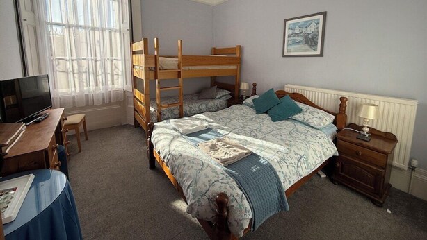 A bedroom with bunk beds, a desk with a computer, and a window with sheer curtains. - Spring Garden Guest House (Gosport)