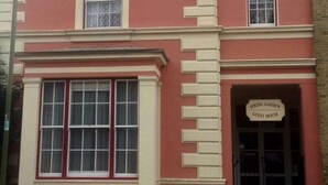 A building with a red facade, a large window with white frames, and a sign reading "Spring Garden Guest House". - Spring Garden Guest House (Gosport)