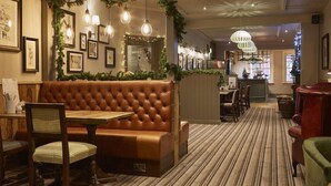 Un restaurant chaleureux avec des banquettes en cuir capitonné, des chaises en bois et un tapis à rayures.