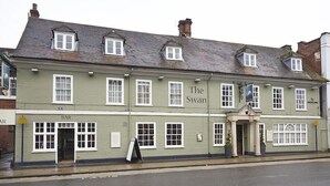 Un bâtiment traditionnel portant une enseigne représentant un cygne, indiquant qu’il s’agit d’un pub ou d’un restaurant.