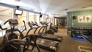 Une salle de sport équipée de tapis de course, de vélos elliptiques et d’haltères.