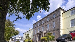 A building with a stone facade, a flag, and a parked car. - Celtic Royal (Caernarfon)