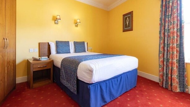 A hotel room with a bed, nightstand, and wardrobe. - Celtic Royal (Caernarfon)