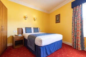 Quarto de hotel com cama, mesa de cabeceira e guarda-roupa.