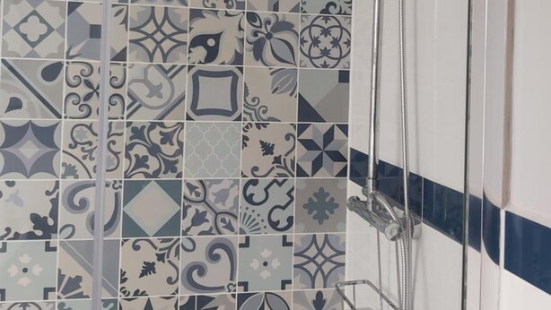 A bathroom with a shower area featuring a variety of patterned tiles. - Northwick Hotel (Evesham)