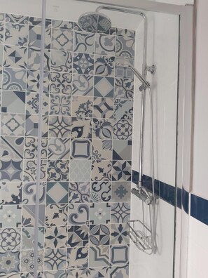 A bathroom with a shower area featuring a variety of patterned tiles. - Northwick Hotel (Evesham)