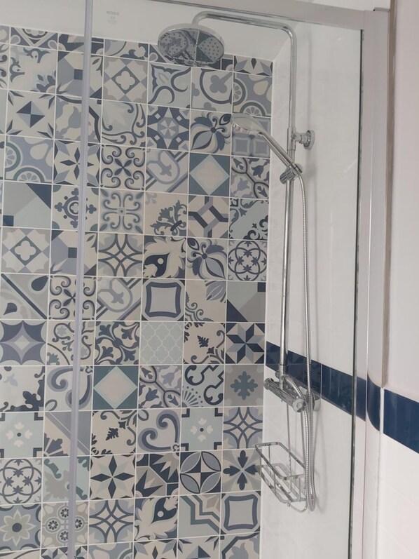A bathroom with a shower area featuring a variety of patterned tiles. - Northwick Hotel (Evesham)