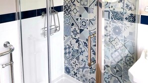 A modern bathroom with a glass shower enclosure, patterned tiles, and a white sink. - Northwick Hotel (Evesham)