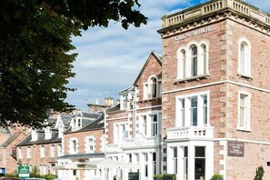 Ein historisches Gebäude mit der Aufschrift 'Glen Mhor Hotel' an der Fassade, das klassische Architektur mit Bogenfenstern und einem markanten Eingang zeigt.