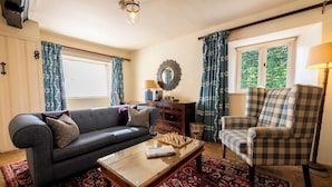 A living room with a sofa, armchair, coffee table, and a chessboard. - The Bay Tree (Burford)