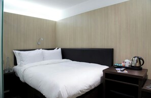 A hotel room with a bed, a nightstand, a coffee maker, and a wall-mounted lamp. - Z Hotel Liverpool (Liverpool)