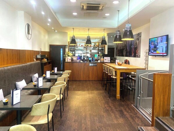 Un restaurant avec des banquettes, des tables et un coin bar.