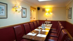 A conference room with a long table, red leather chairs, and wall-mounted lamps. - Royal Hotel (Liverpool)