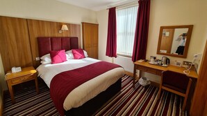 A hotel room with a large bed, a desk, a mirror, and a window with curtains. - Royal Hotel (Liverpool)