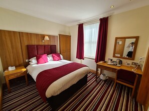 A hotel room with a large bed, a desk, a mirror, and a window with curtains. - Royal Hotel (Liverpool)
