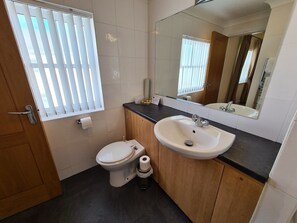 A bathroom with a toilet, sink, and mirror. - Royal Hotel (Liverpool)
