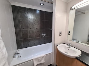A bathroom with a bathtub, a sink, and a mirror. - Royal Hotel (Liverpool)
