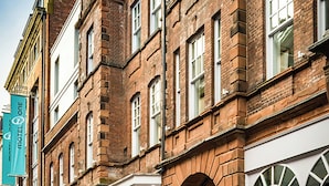 A row of brick buildings with storefronts, a cobblestone street, and a clear sky. - Motel One (Newcastle-upon-Tyne)