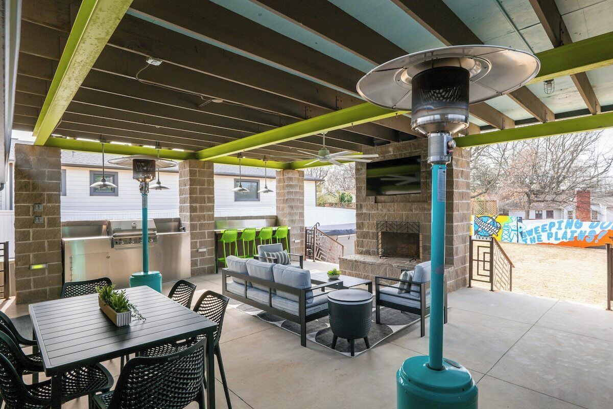 An outdoor patio with a grill, seating area, and a large heater.