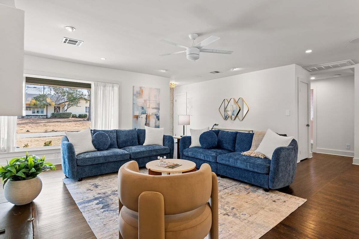 Ein modernes Wohnzimmer mit zwei blauen Sofas, einem beigen Sessel und einem Couchtisch.