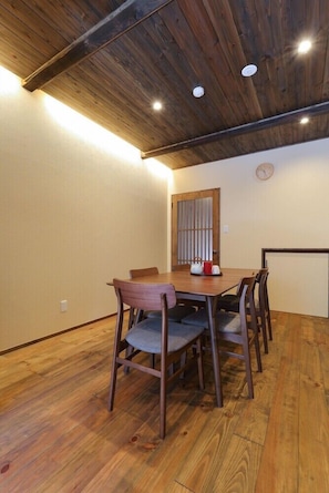A dining area with a wooden table and chairs, a wooden ceiling, and a clock on the wall. - Kanazawa no Yado Ikedaya [vr] (Kanazawa)