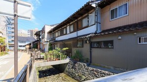 A traditional Japanese residential building with a stone water feature, wooden balconies, and a tiled roof. - Kanazawa no Yado Ikedaya [vr] (Kanazawa)