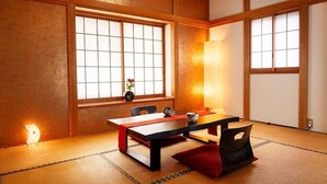 Een traditionele Japanse kamer met tatami vloerbedekking, een lage tafel met een rode loper en schuifdeuren met uitzicht op een tuin.
